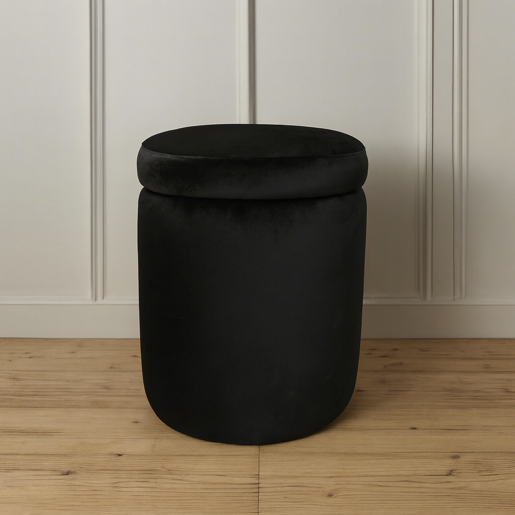 Black cylindrical storage ottoman on a wooden floor with a white paneled wall background