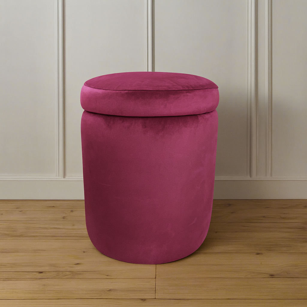 Pink cylindrical ottoman on a wooden floor with a neutral wall background