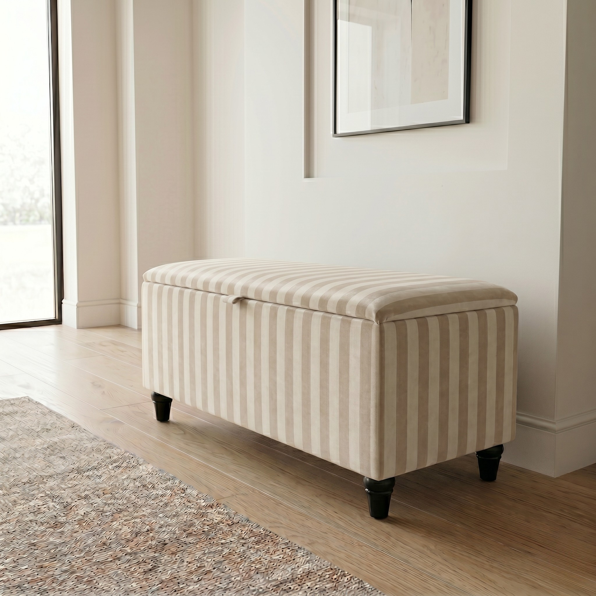 Beige cream Striped ottoman in a room with a window and framed picture on the wall.