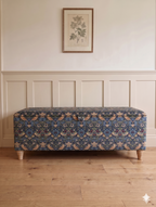 William Morris Strawberry Print ottoman in navy in a hallway with wooden floor and panelled walls