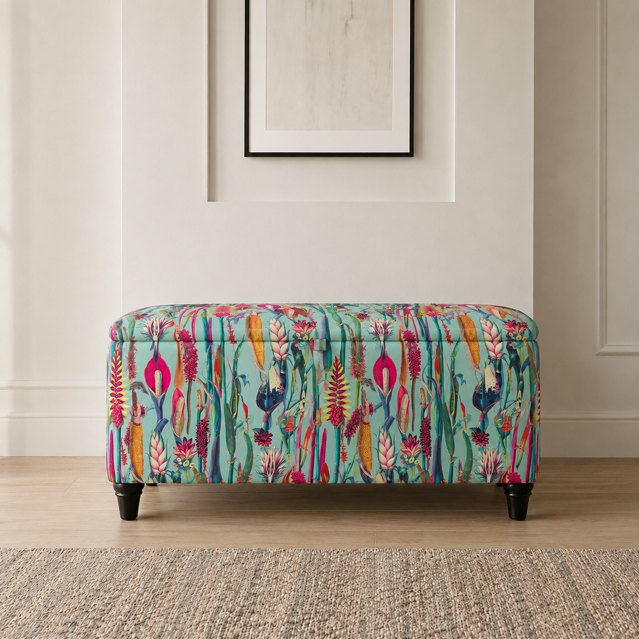 A rectangular upholstered bench with a colorful botanical pattern on a mint green background, supported by four dark legs, set in a styled room with a light wood floor and a neutral wall.