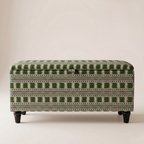 An upholstered storage bench or ottoman with a green and off-white geometric pattern, supported by four dark legs, photographed against a neutral beige background.