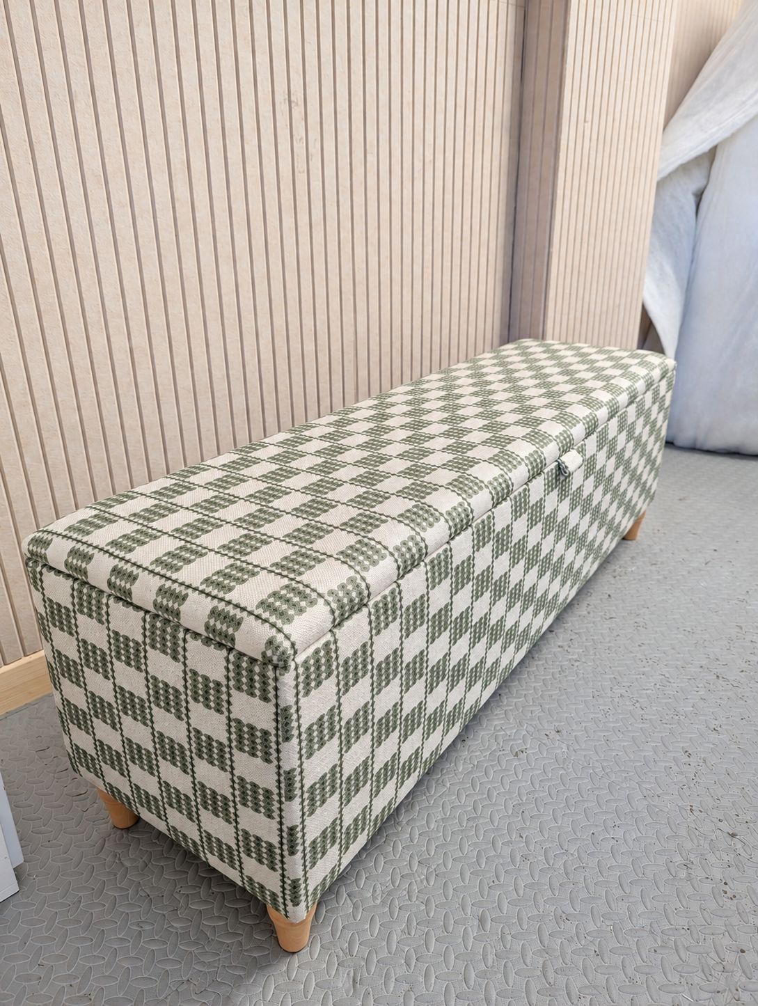 workshop image of a storage bench upholstered in a green and cream checkered linen by iLiv called Flint.