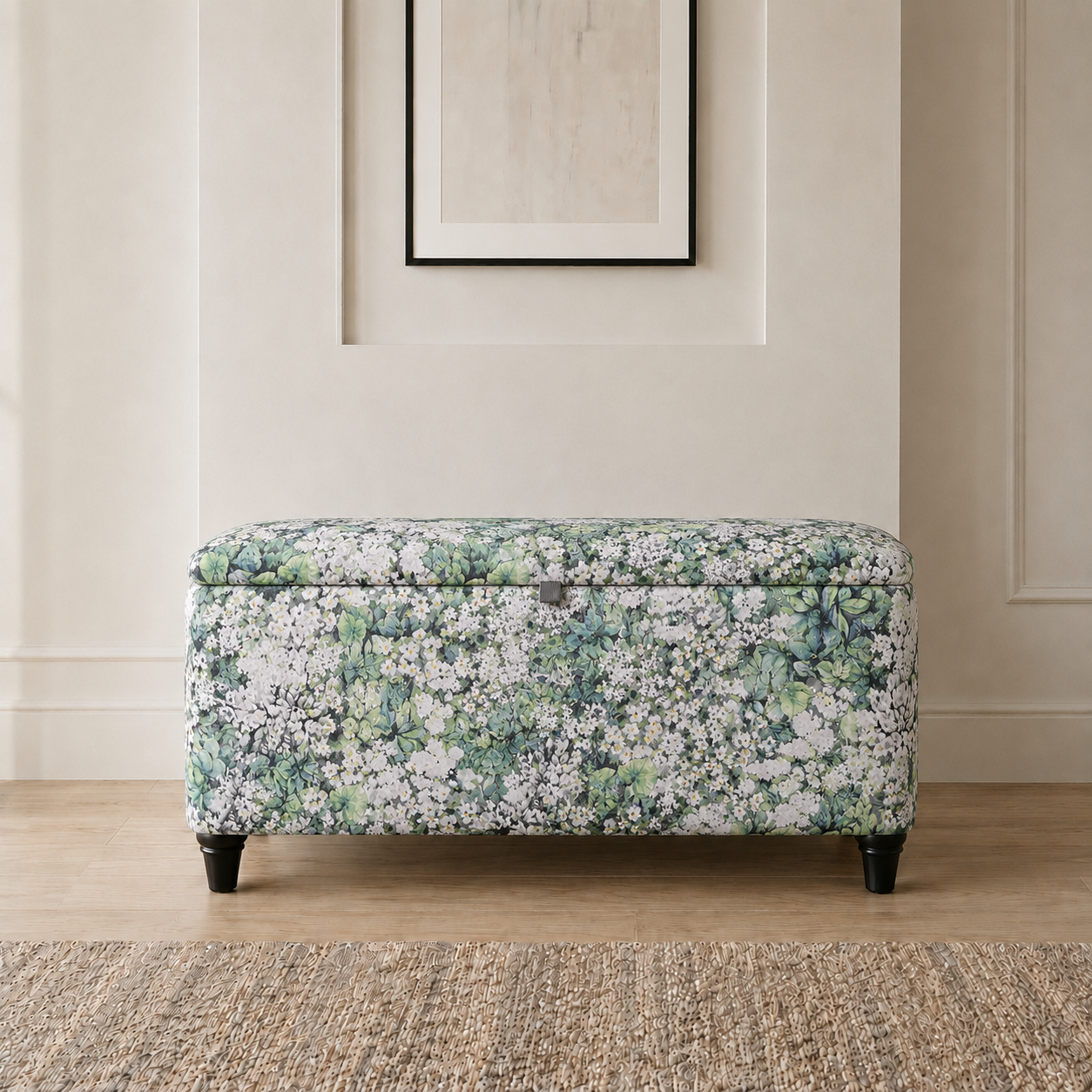 A rectangular upholstered storage bench with a green and white floral pattern, standing on black legs in a styled room setting.