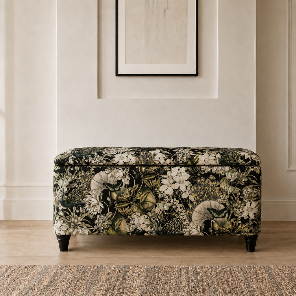 A rectangular upholstered bench with a dark floral and botanical pattern in black, cream, and olive green, standing on short dark legs in a styled interior setting.