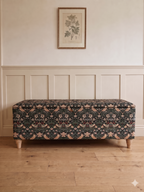 Storage bench in Black Strawberry thief William morris fabric on a light wooden floor with panelled walls behind