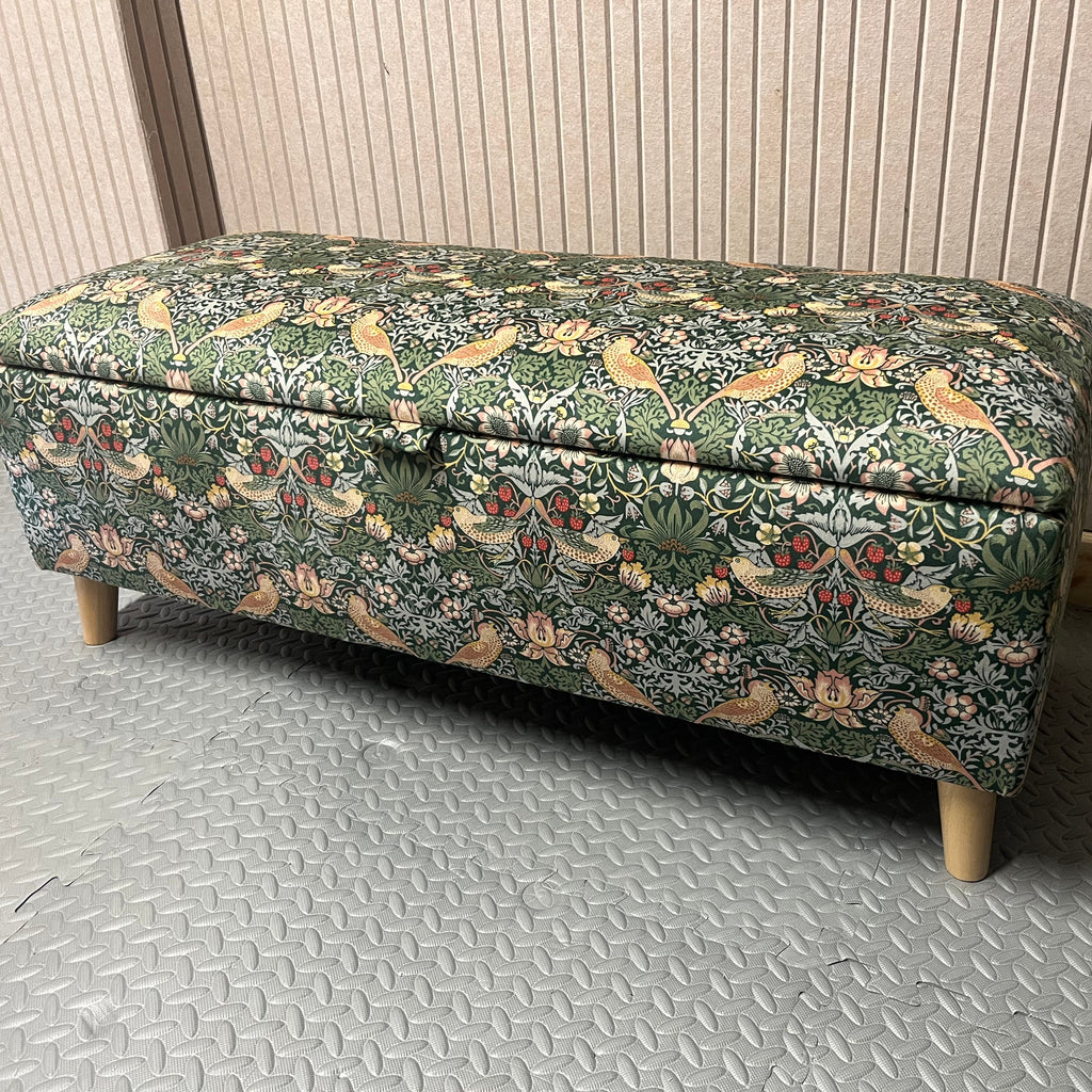 Floral-patterned storage bench on a metallic floor with a neutral wall background