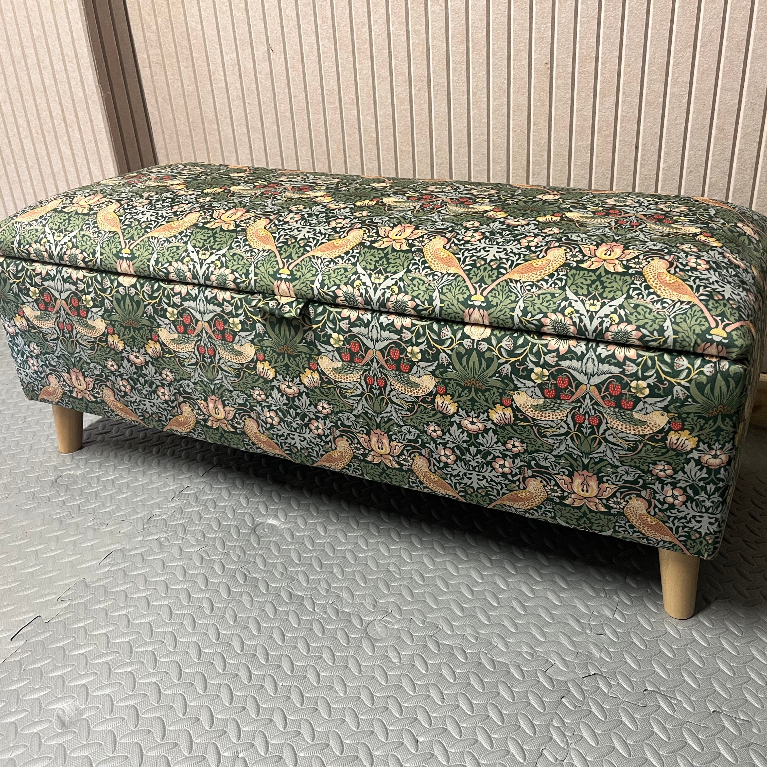 Floral-patterned storage bench on a metallic floor with a neutral wall background