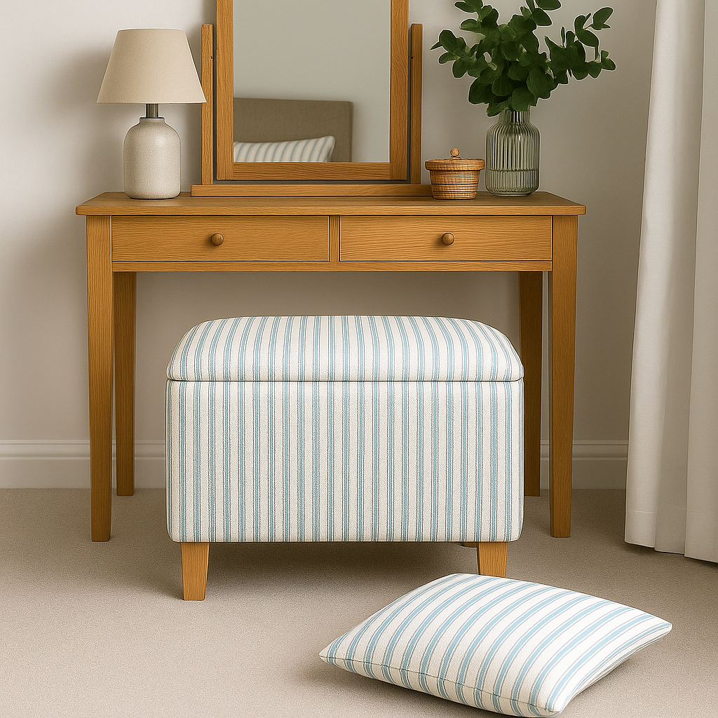 Wooden dressing table with mirror, lamp, and striped ottoman and pillow in a room setting.