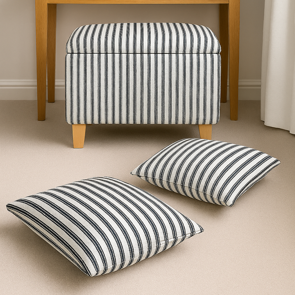 Striped ottoman and cushions on a beige floor with a wooden table in the background.