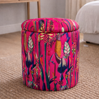 Colorful patterned ottoman in a room with a desk and window.