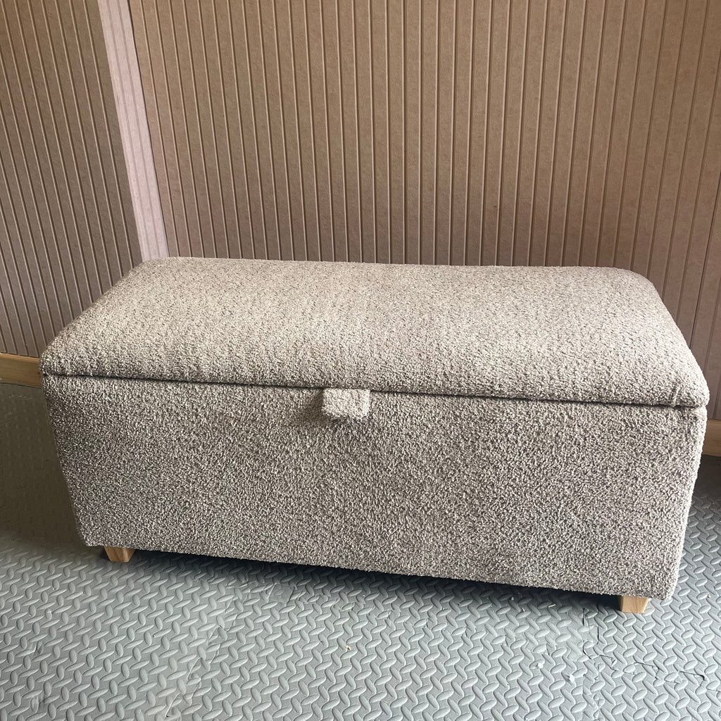 Gray textured ottoman against a pink slat patterned wall