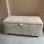 Gray textured ottoman against a pink slat patterned wall