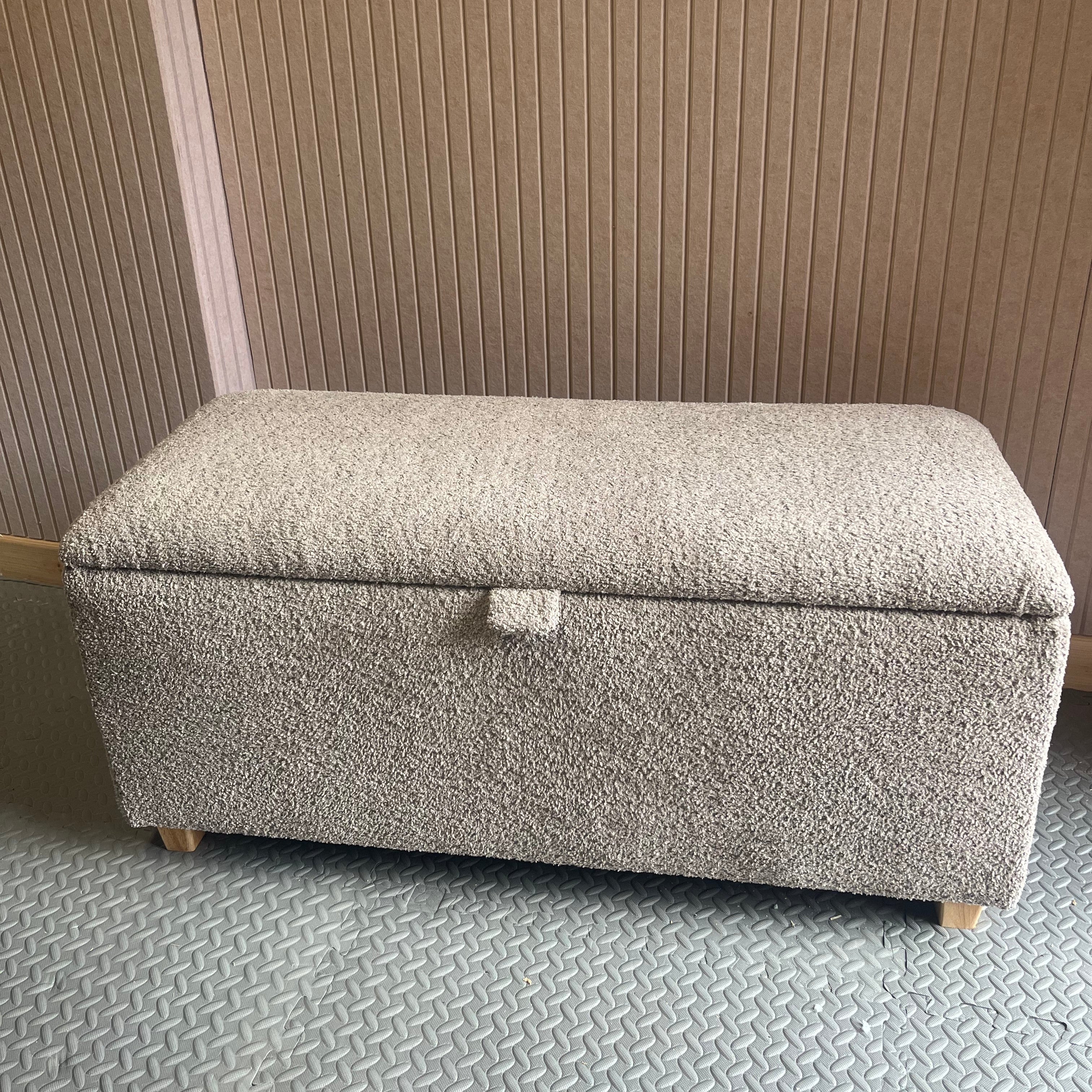 Gray textured ottoman against a pink slat patterned wall
