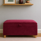 Red storage ottoman against a neutral wall with a shelf in the background.