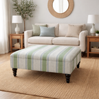 Living room with a striped ottoman in Linwood stripes, beige sofa, and decorative items.