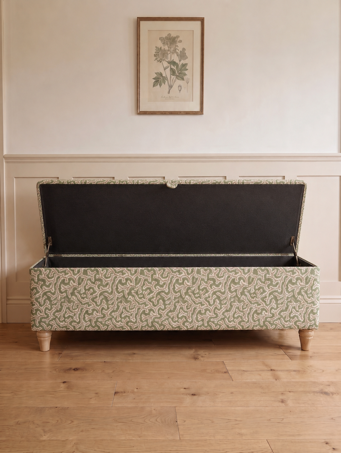 Patterned storage bench in big Dulcie linen with open lid in a room with wooden flooring and a framed picture on the wall.