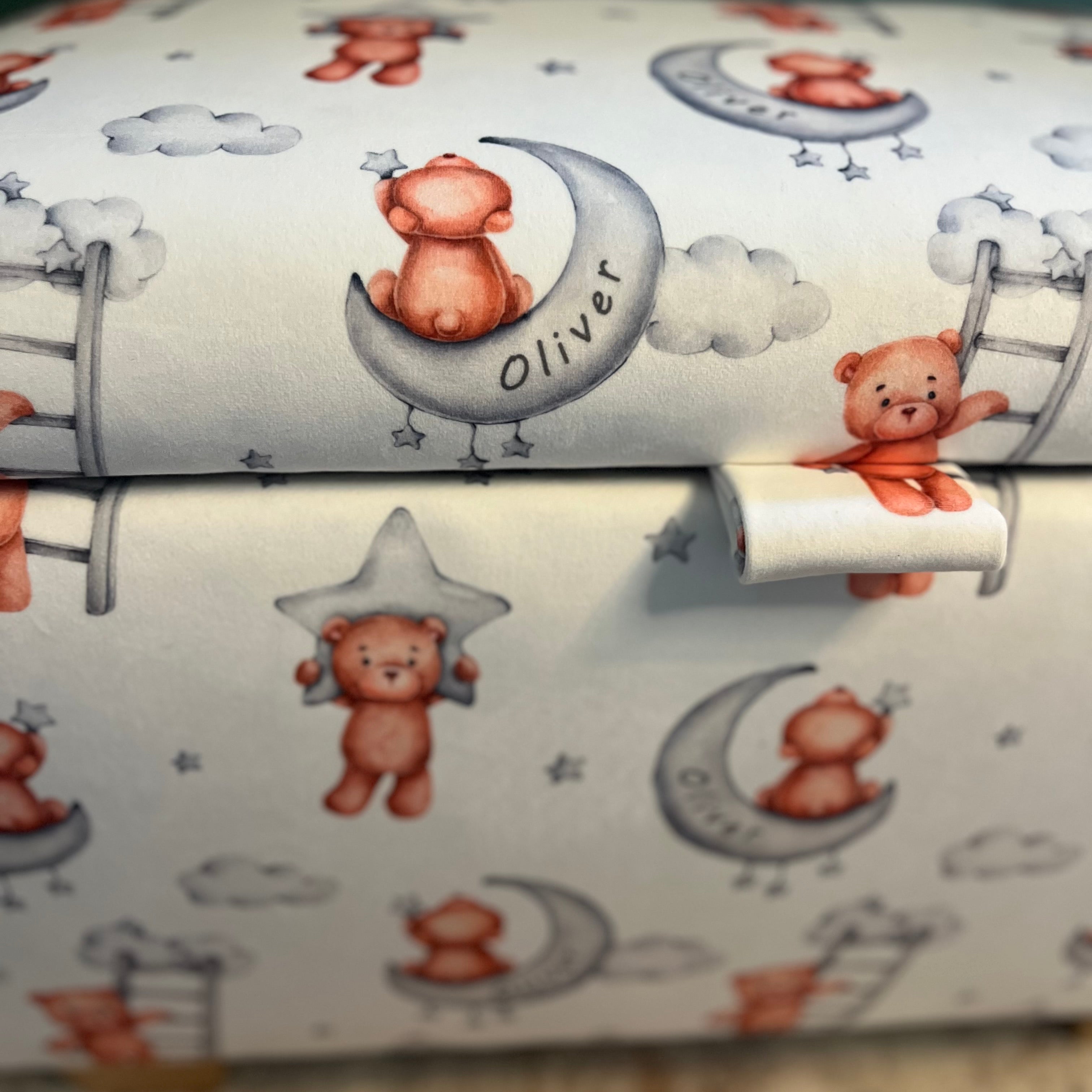 personalised childrens fabric with white background and brown teddy bears on. The bears are hanging off of moons and stars which have 'Oliver' written on them and can be personalised to a childs name.