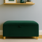 Green ottoman in a room with a shelf featuring a framed picture, vase, and plant.