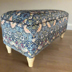 Fabric-covered wooden bench with floral pattern on a wooden floor.