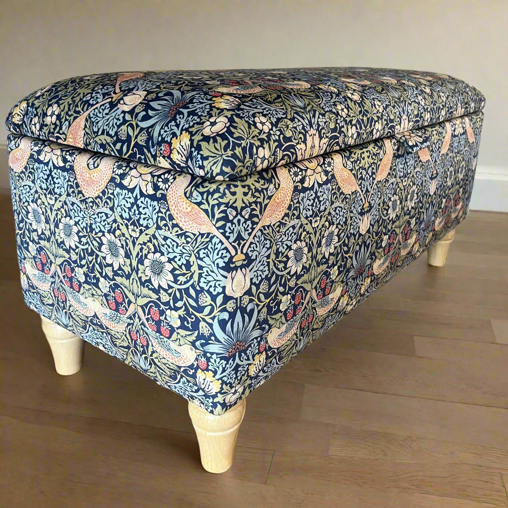 Fabric-covered wooden bench with floral pattern on a wooden floor.
