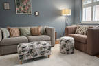 Living room with gray sofa, brown armchair, and Utopia Pink patterned storage ottomans.