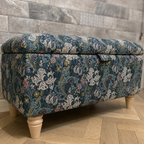 William Morris Letchworth ottoman in golden lily velvet on a parquet wooden flooring with tiles behind