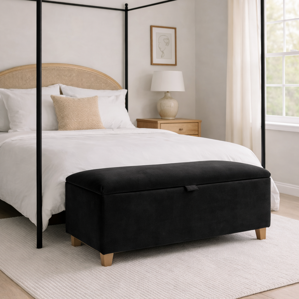 Bedroom with a four-poster bed and black ottoman.