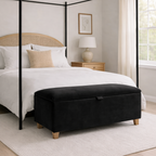 Bedroom with a four-poster bed and black ottoman.
