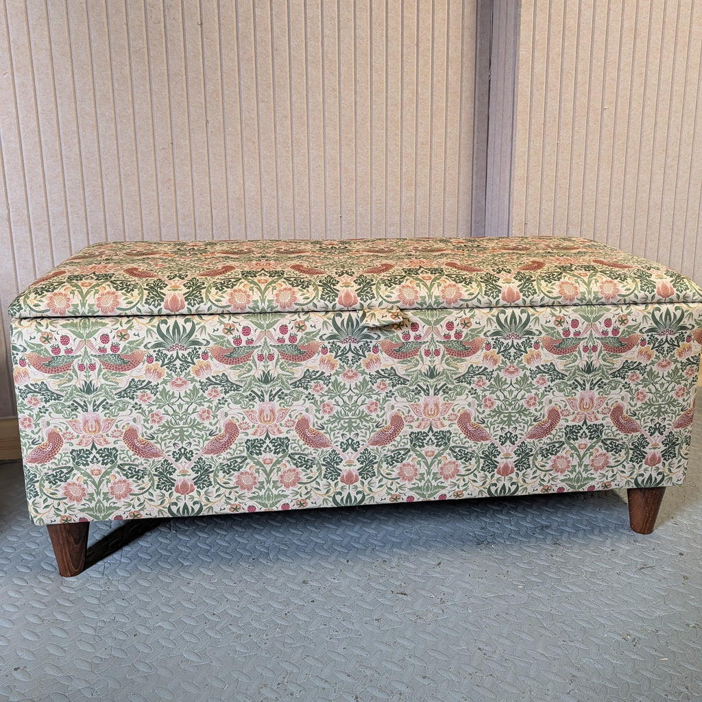 Floral-patterned William Morris strawberry thief storage bench against a neutral wall.