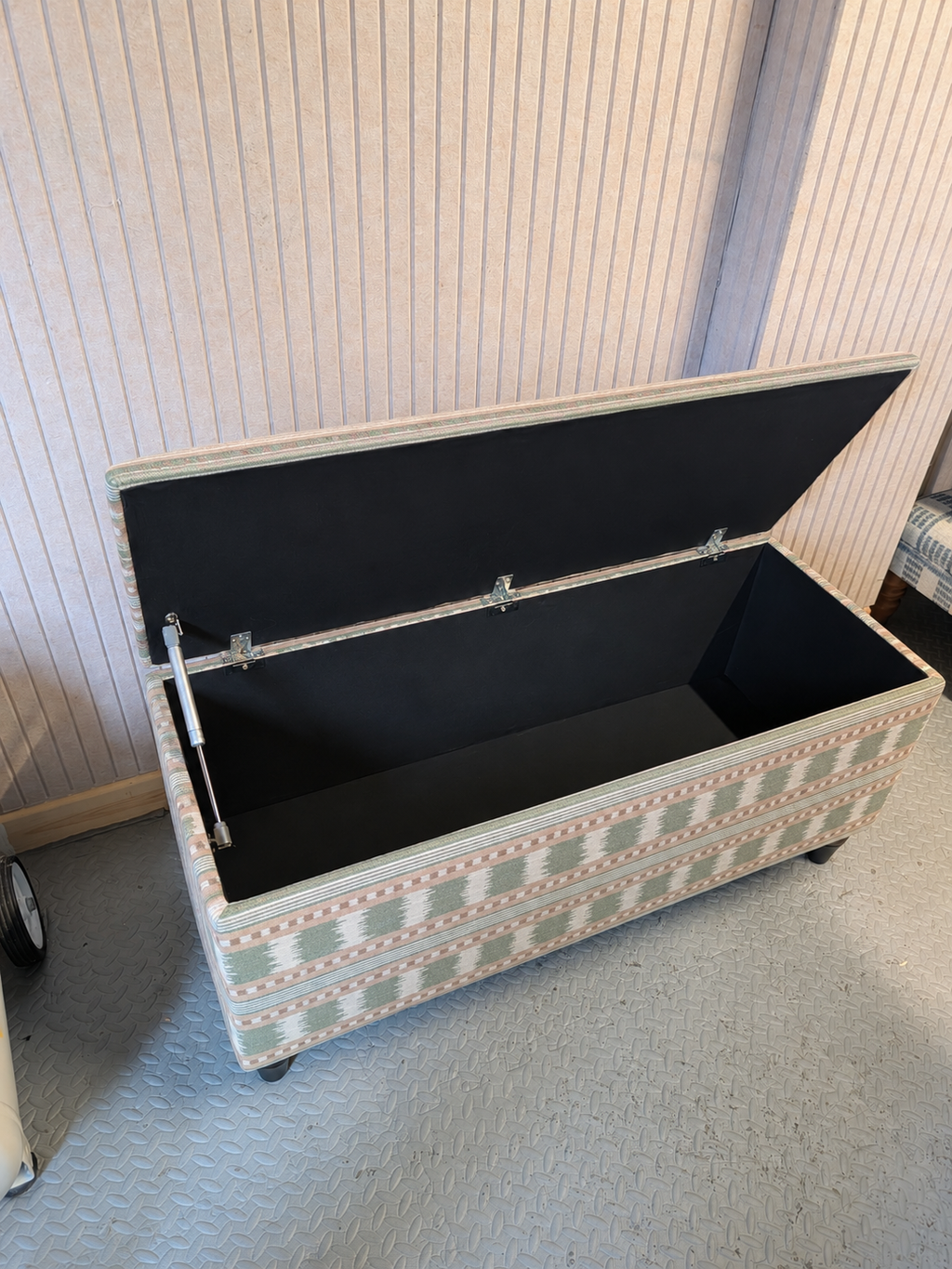 Open storage ottoman in James Hare Paxton fabric in a workshop room.