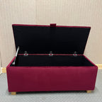 Maroon ottoman with open lid against a textured wall.