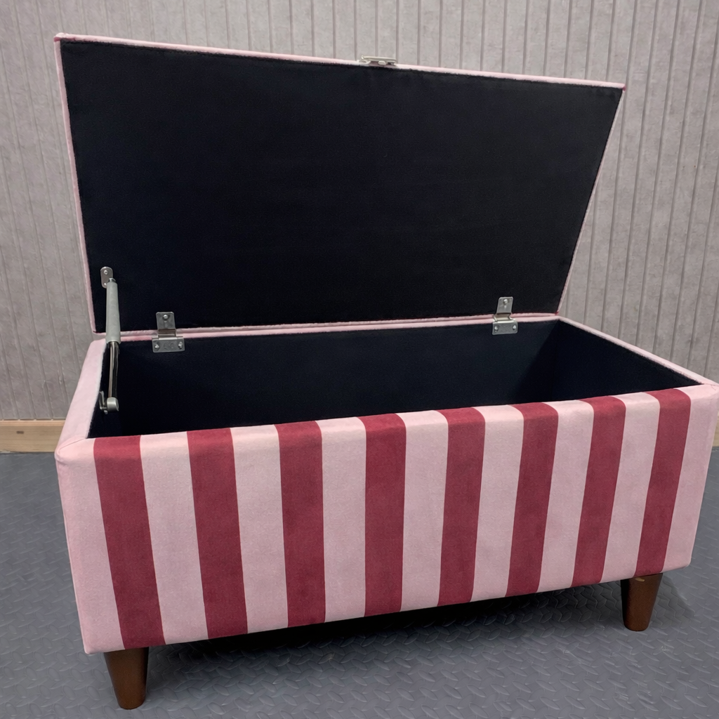 Striped storage bench with open lid on a gray floor.