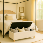 Bedroom with a canopy bed and storage ottoman featuring pillows.
