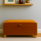 Orange storage bench in a room with a shelf featuring a framed abstract art piece, vase, and plant.