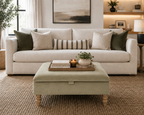 A styled living room scene featuring a cream-colored upholstered sofa with multiple decorative throw pillows, a matching light green ottoman coffee table in the foreground, and a woven rug on the floor.
