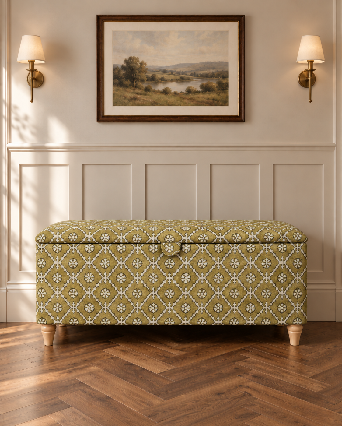 A storage bench with a green and beige floral patterned fabric upholstery, styled in a traditional room setting with a wooden herringbone floor, white wainscoting, and wall sconces.
