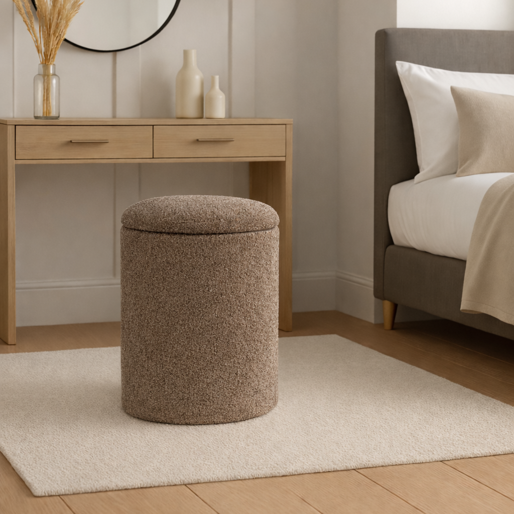 Brown textured ottoman in a bedroom setting with a bed, desk, and wall lamp.
