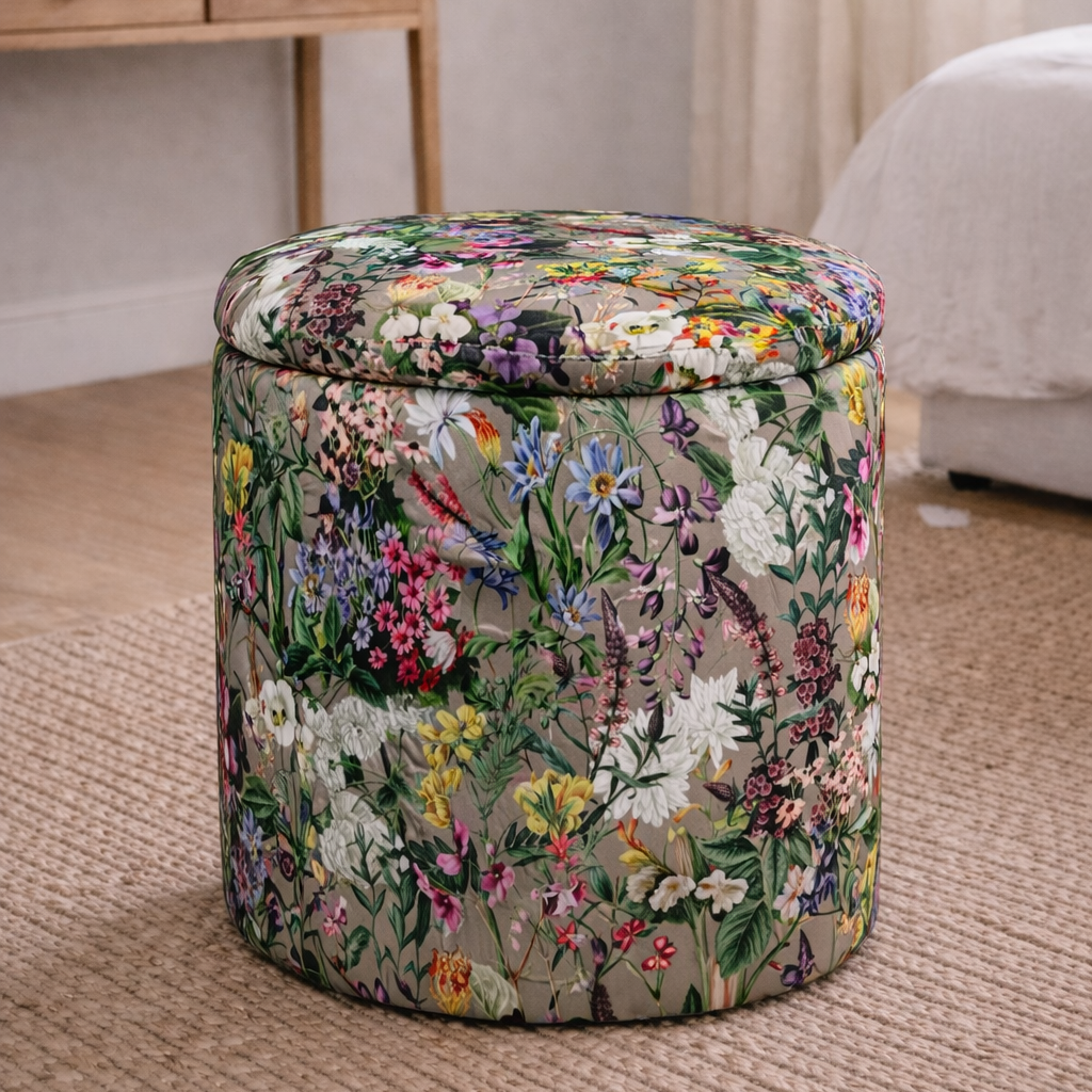 Floral-patterned ottoman in a room with a desk and curtains.