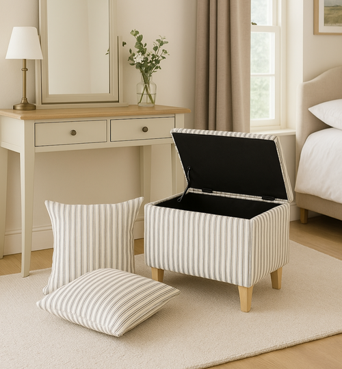 Striped ottoman with open lid in a bedroom setting with a mirror, lamp, and bed.
