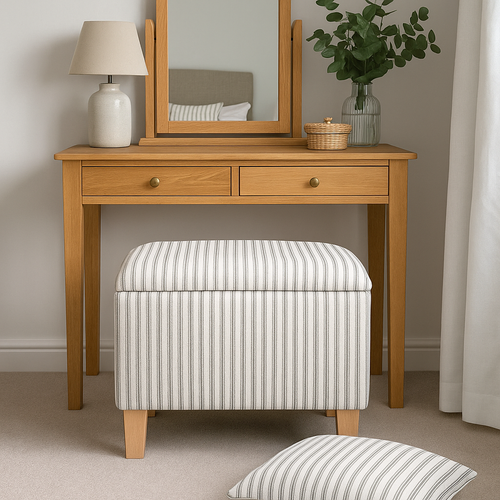 Wooden dressing table with mirror, lamp, and striped ottoman in a room setting.