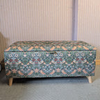 Floral William Morris patterned storage bench against a striped wall.