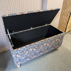 Floral-patterned storage trunk with a black interior on a gray floor.