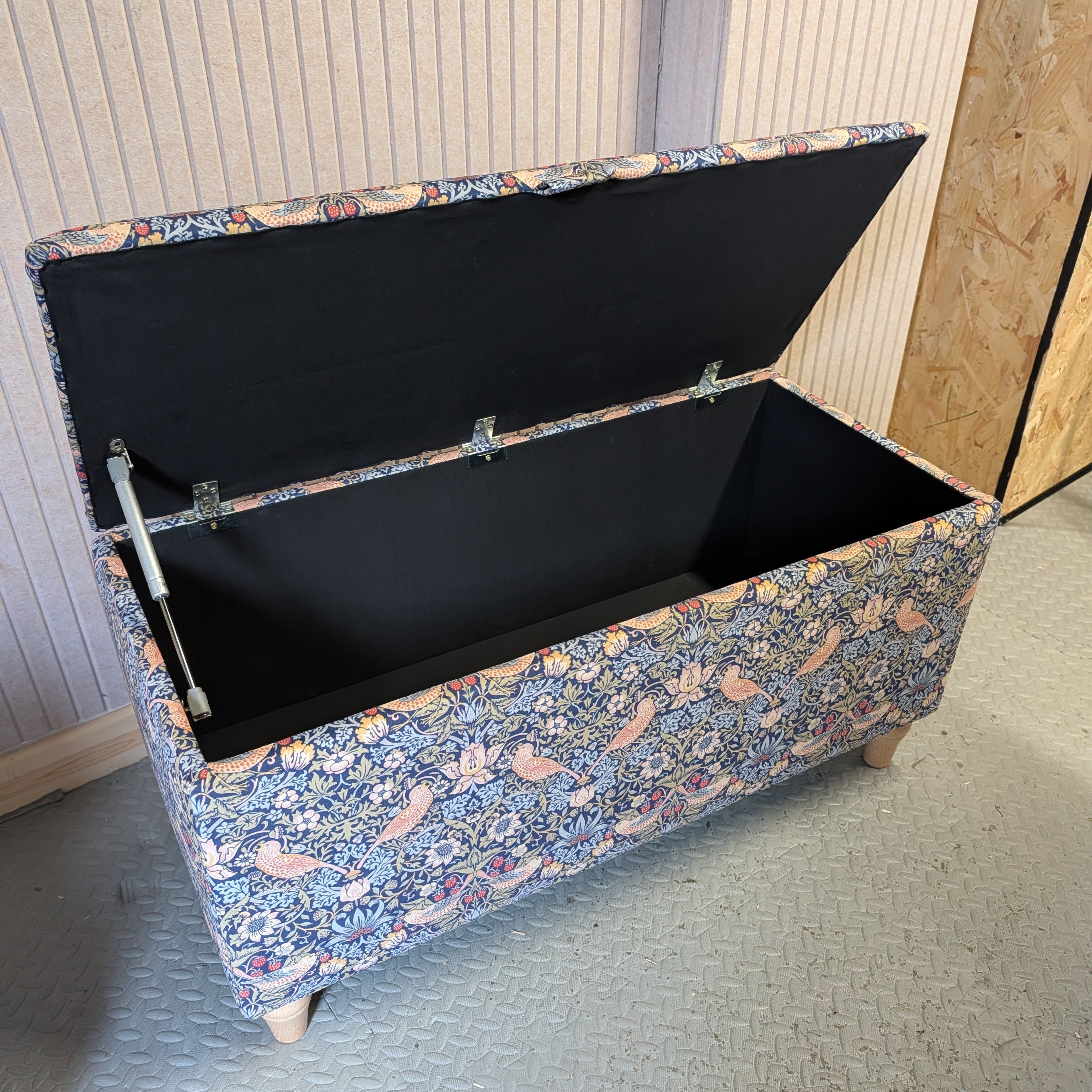 Floral-patterned storage trunk with a black interior on a gray floor.