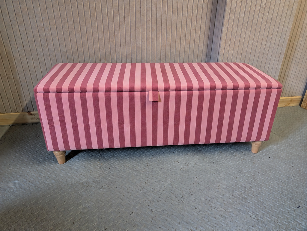 Pink striped storage bench on a gray floor with a wooden wall background