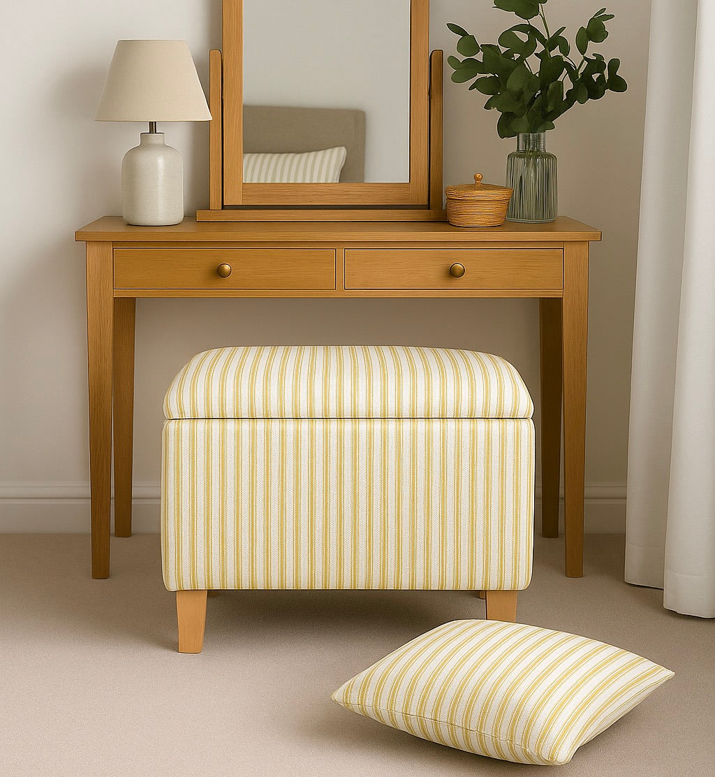 Wooden dressing table with mirror, lamp, and striped ottoman and pillow in a room setting.