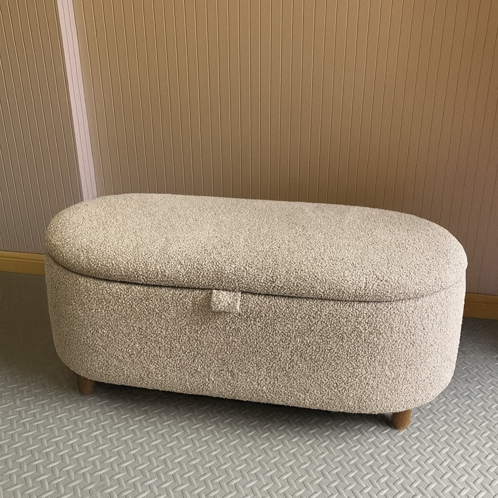 Beige ottoman with a textured bouclé surface on a patterned floor with slatted background wall.