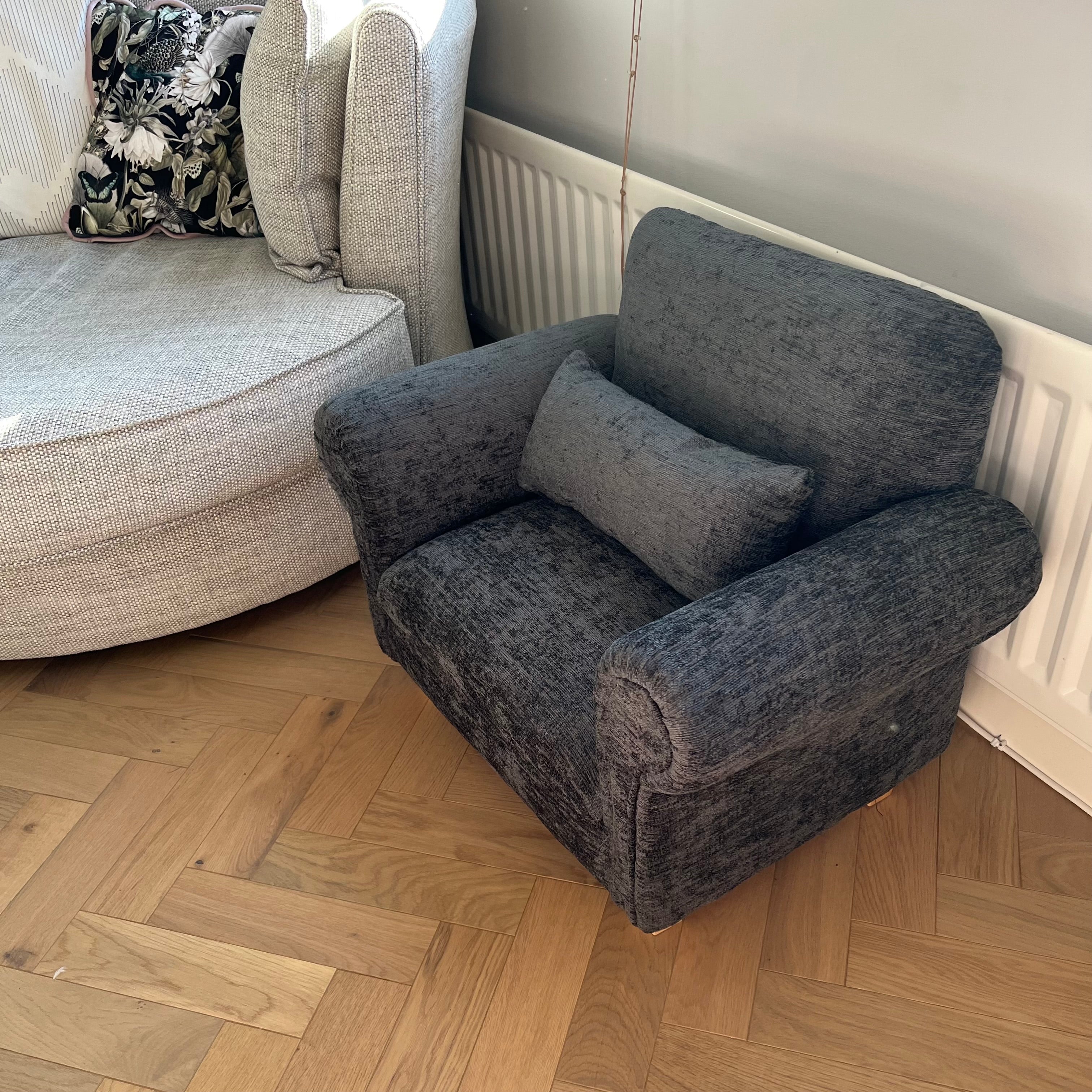 black mini sofa with cushion next to a regular sofa